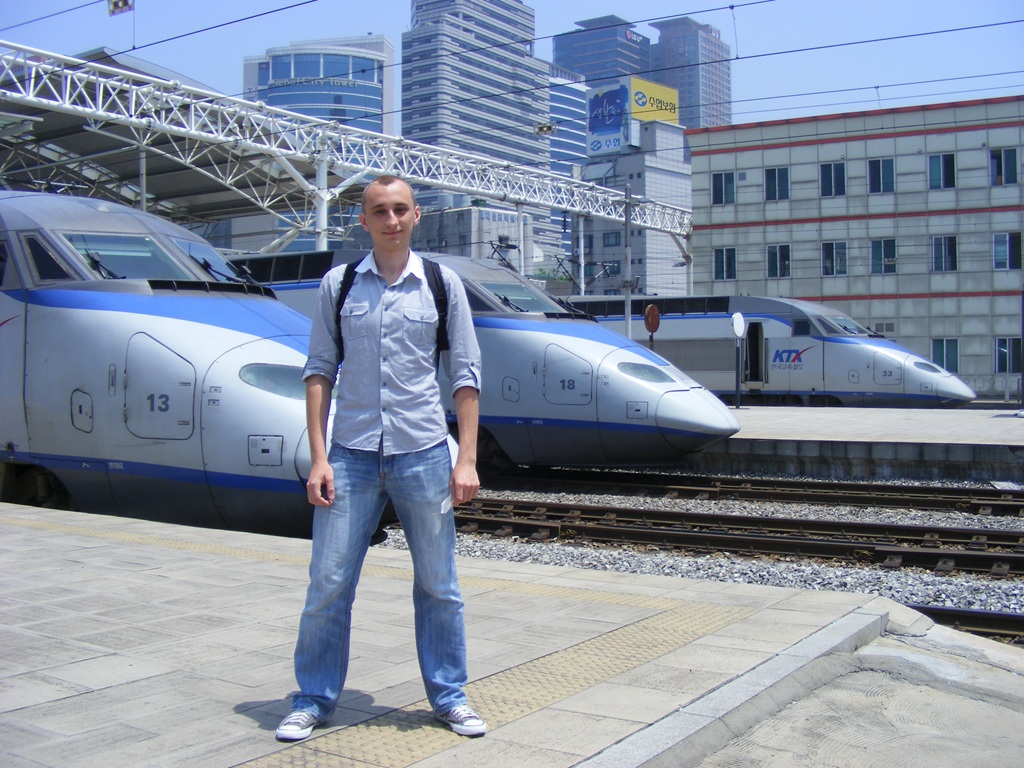 Денис на пероні поруч із швидкісними поїздами KTX (Korea Train Express) на станції Сеул у Південній Кореї